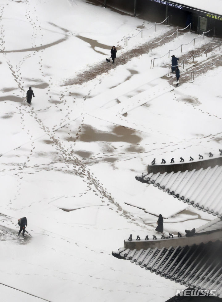 [서울=뉴시스] 김명원 기자 = 22일 오전 서울 종로구 경복궁에 간밤에 내린 하얀 눈이 쌓여 있는 가운데 직원들이 눈을 치우고 있다. 2024.02.22 kmx1105@newsis.com