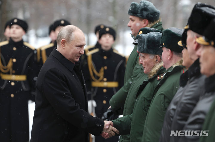[모스크바=AP/뉴시스] 블라디미르 푸틴(왼쪽) 러시아 대통령이 23일(현지시각) '조국 수호자의 날'을 맞아 모스크바에 있는 무명용사 묘지 헌화식에 참석해 육군 참전용사들과 악수하고 있다. 2024.02.24.