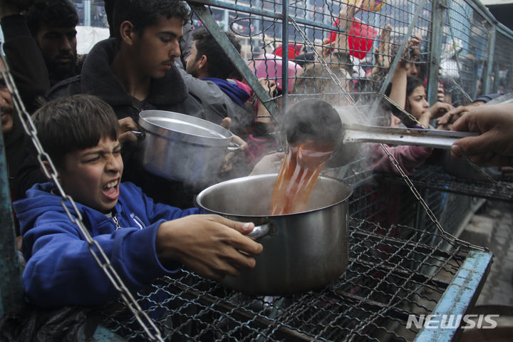[가자지구=AP/뉴시스] 지난 18일(현지시각) 가자지구 자발리아 난민촌 무료 급식소에서 팔레스타인 소년이 음식을 받고 있다. 2024.03.22.