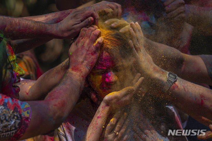 [뭄바이=AP/뉴시스] 25일(현지시각) 인도 뭄바이에서 열린 홀리 축제에 참가한 참가자들이 한 소녀의 얼굴에 색 가루를 발라주고 있다. 2024.03.26.