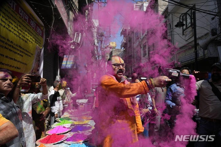 [잠무=AP/뉴시스] 25일(현지시각) 인도 잠무에서 열린 홀리 축제에 참가한 한 남성이 색 가루를 뿌리고 있다. 2024.03.26.