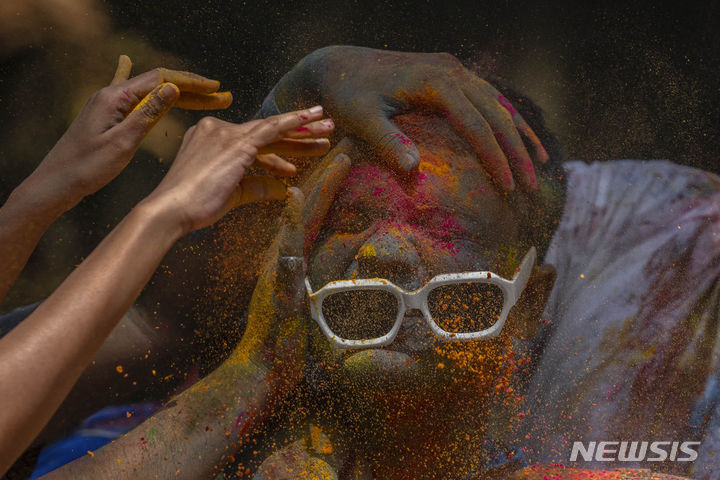 [뭄바이=AP/뉴시스] 25일(현지시각) 인도 뭄바이에서 열린 홀리 축제에 참가한 참가자들이 한 소년의 얼굴에 색 가루를 발라주고 있다. 2024.03.26.