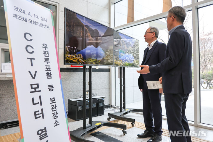 [창원=뉴시스]이용균(왼쪽) 경남선관위원장이 지난 25일 도선관위 1층 로비에서 우편투표함 등 보관장소 CCTV영상 확인용 대형모니터 설치 현장을 점검하고 있다.(사진=경남선관위 제공) 2024.03.26. photo@newsis.com