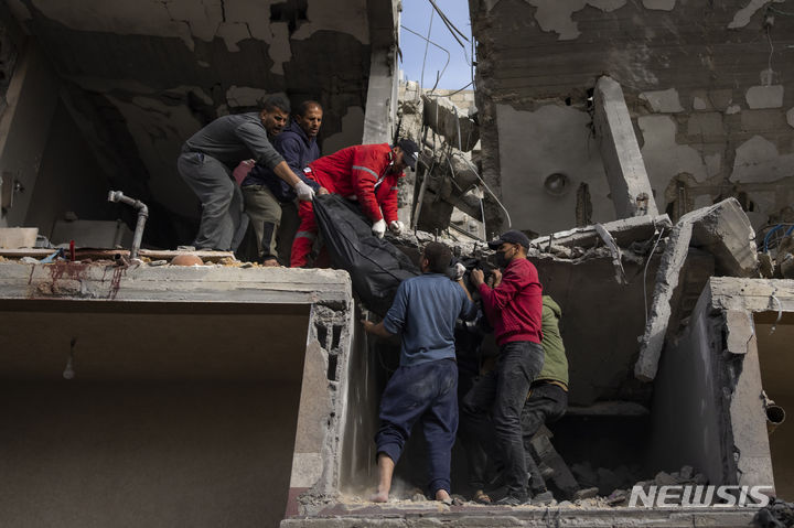 [라파=AP/뉴시스] 27일(현지시각) 가자지구 라파에서 팔레스타인 주민들이 이스라엘군의 공습으로 파괴된 건물 잔해에서 발견된 여성의 시신을 옮기고 있다. 2024.03.27.