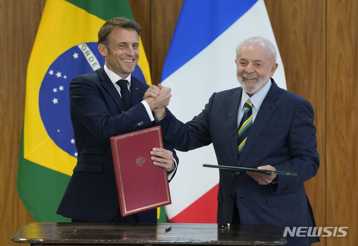 [브라질리아=AP/뉴시스] 루이스 이나시우 룰라 다시우바(오른쪽) 브라질 대통령과 에마뉘엘 마크롱 프랑스 대통령이 28일(현지시각) 브라질리아 플라날토 대통령궁에서 협정문에 서명한 뒤 악수하고 있다. 2024.03.29.