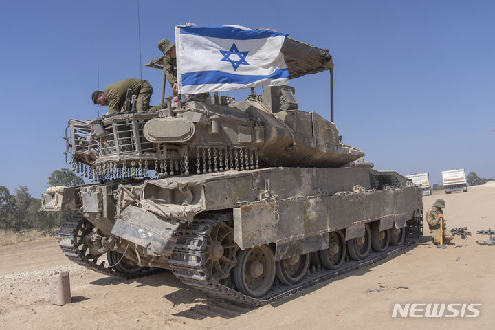 [가자지구=AP/뉴시스] 15일(현지시각) 이스라엘 남부, 가자지구 국경 인근에 주둔 중인 이스라엘 군인이 무장병력수송장갑차(APC)에 국기를 부착하고 있다. 2024.04.16.