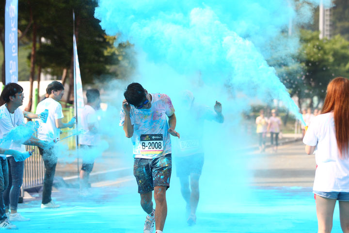 [부산=뉴시스] 컬러레이스 참가자가 블루 파우더를 맞으며 달리고 있다. (사진=한국마사회 제공) 2024.04.15. photo@newsis.com *재판매 및 DB 금지
