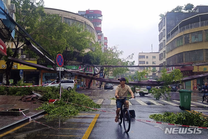 [칭위안=AP/뉴시스] 22일(현지시각) 중국 남부 광둥성 칭위안시에서 자전거를 탄 주민이 폭우 여파로 도로에 쓰러진 나무 잔해를 지나고 있다. 현지 당국은 지난 19일부터 광둥성에 쏟아진 폭우로 강이 범람해 지금까지 최소 10명이 숨지고 11만 명이 대피했다고 전했다. 2024.04.23.