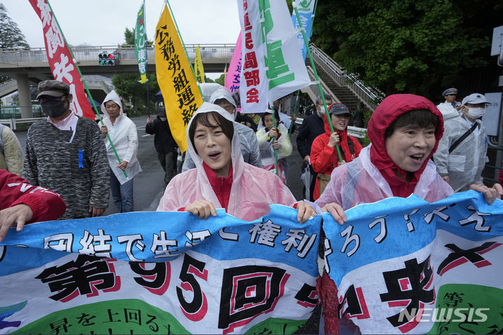 [도쿄=AP/뉴시스] 1일 일본 도쿄에서 열린 국제 노동자의 날 집회 참석자들이 현수막과 깃발을 들고 행진하고 있다. 2024.05.02.