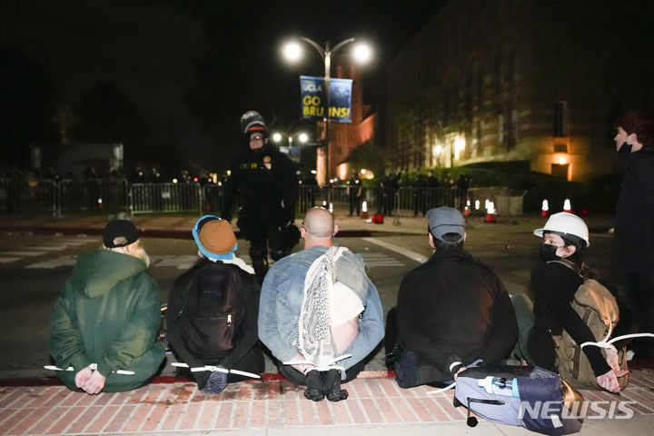 [AP/뉴시스] 2일 새벽 미국 로스앤젤레스 UCLA 캠퍼스에서 경찰이 진입해 텐트 농성 중이던 반 이스라엘 시위대 학생들을 붙잡아 체포하고 있다. 학생들 손을 등 뒤로 돌려 지퍼타이로 묶어놓았다