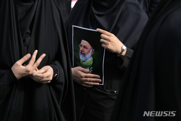 [테헤란=AP/뉴시스]20일(현지시각) 이란 수도 테헤란에서 한 여성이 에브라힘 라이시 대통령 추모 행사에 참석해 그의 포스터를 들고 있는 모습. 2024.05.21.