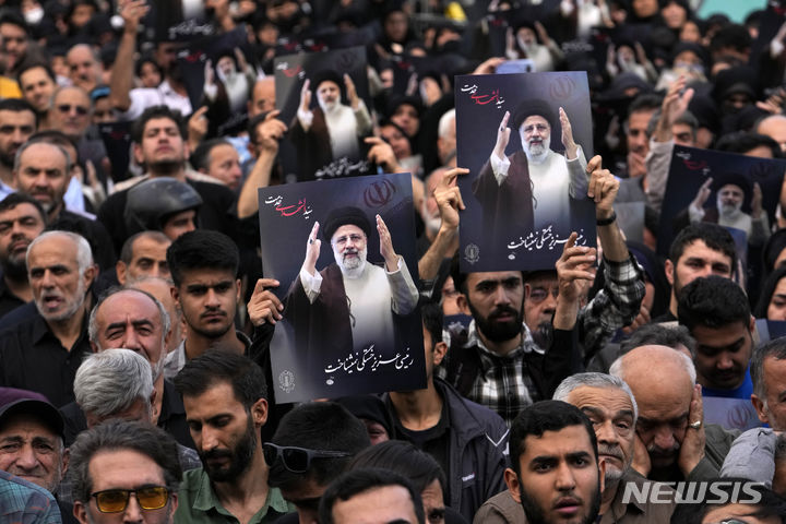 [테헤란=AP/뉴시스] 20일(현지시각) 이란 테헤란의 발리-에-아스르 광장에서 에브라힘 라이시 대통령의 사진을 든 사람들이 고인을 애도하고 있다. 라이시 대통령은 아미르 압돌라히안 외무장관 등과 함께 19일 헬리콥터 추락 사고로 사망했으며 장례식은 오는 23일 그의 고향인 북동부 마슈하드에서 열릴 것으로 알려졌다. 2024.05.21.