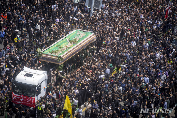 [테헤란=AP/뉴시스] 22일(현지시각) 이란 수도 테헤란에서 열린 고 에브라힘 라이시 대통령과 헬기 추락 사고 희생자들의 장례식에서 시민들이 운구 차량을 따라가고 있다. 2024.05.23.