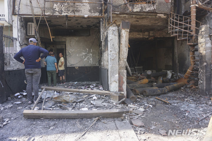 [=AP/뉴시스]사람들이 26일(현지시각) 인도 뉴델리에 있는 한 아동병원의 불탄 건물을 바라보고 있다. 25일 밤에 병원에서 화재가 발생해 7명의 신생아가 사망했다고 소방당국이 26일 밝혔다. 2024.05.26. 