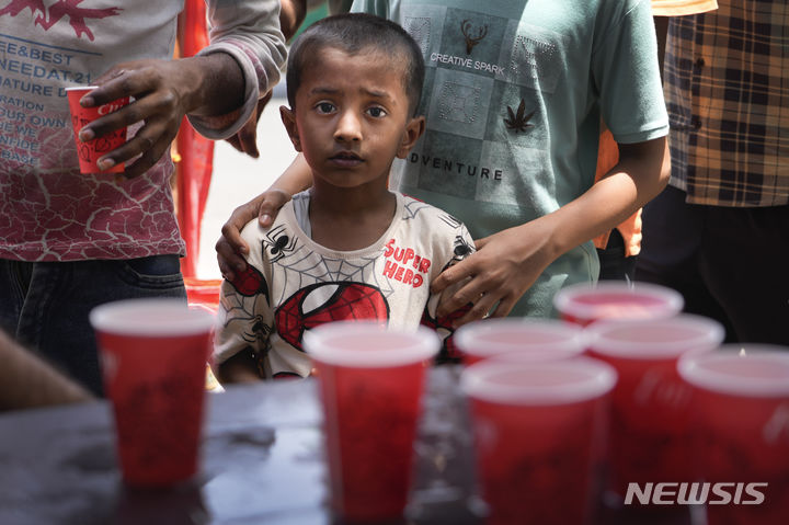 [뉴델리(인도)=AP/뉴시스]인도 수도 뉴델리에서 30일 한 소년이 비정부기구가 무료로 나눠주는 차가운 음료수 한 잔을 받기 위해 기다리고 있다. 인도 법원이 수 주 동안 계속된 폭염으로 인한 사망자가 수백명에 이르자 정부에 국가 비상사태를 선포할 것을 촉구했다고 AFP 통신이 31일 보도했다. 2024.05.31.