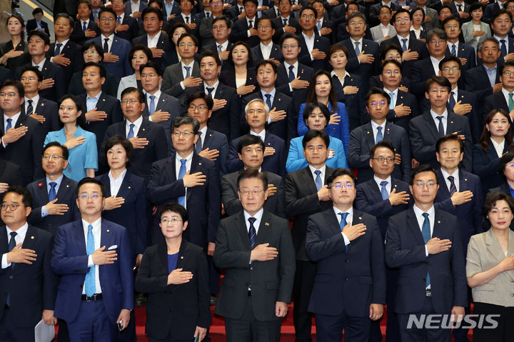 [서울=뉴시스] 조성우 기자 = 이재명 더불어민주당 대표와 박찬대 원내대표 등 의원들이 제22대 국회 임기 시작일인 30일 오후 서울 여의도 국회 로텐더홀에서 열린 의원총회에서 국기에 대한 경례를 하고 있다. 2024.05.30. xconfind@newsis.com