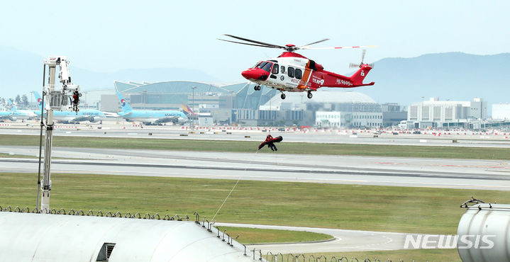 [인천공항=뉴시스] 김선웅 기자 = 인천국제공항 활주로에서 착륙 시도 항공기와 원격주기장 이동 차량 추돌로 인한 화재·폭발을 가정해 열린 2024 READY Korea 2차 훈련에서 소방헬기를 통한 인명구조가 진행되고 있다. (공동취재) 2024.06.05. photo@newsis.com