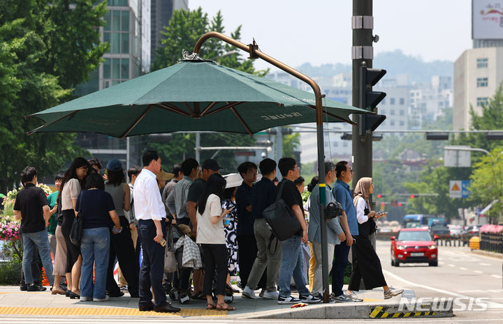 [서울=뉴시스] 황준선 기자 = 서울의 낮 기온이 31도까지 오르는 등 무더운 날씨를 보인 11일 오후 서울 종로구 세종대로 사거리에서 신호를 기다리는 시민들이 그늘막 아래에 모여 있다. 2024.06.11. hwang@newsis.com