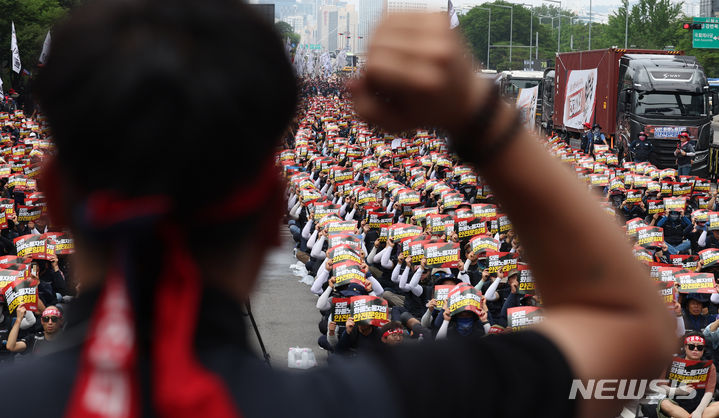 [서울=뉴시스] 추상철 기자 = 15일 오후 서울 영등포구 여의도공원 앞에서 열린 민주노총 공공운수노조 화물연대본부의 '화물노동자 총력투쟁 결의대회'에서 노조원들이 피켓을 들고 단결투쟁가를 부르고 있다. 2024.06.15. scchoo@newsis.com