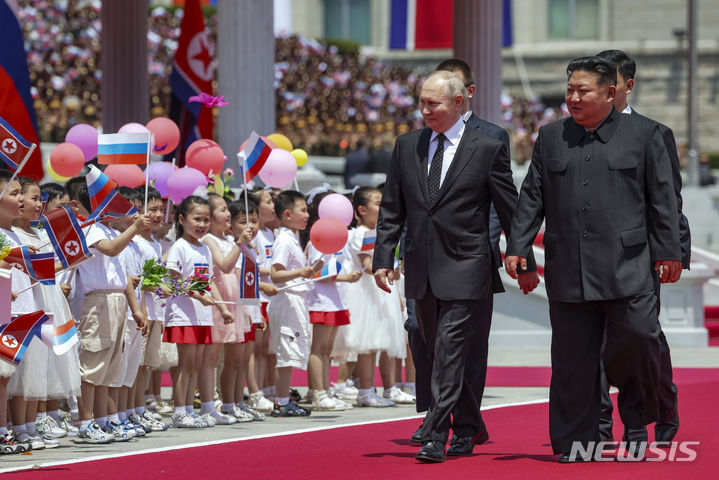 [평양=AP/뉴시스] 블라디미르 푸틴(왼쪽) 러시아 대통령이 19일 김정은 북한 국무위원장과 함께 북한 평양의 김일성 광장에서 열리는 공식 환영식장에 도착해 환영나온 어린이들을 바라보고 있다. 2024.06.19.
