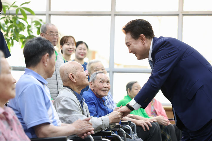 [서울=뉴시스] 최진석 기자 = 윤석열 대통령이 21일 경기 수원시 장안구 수원보훈요양원을 방문해 단체 기념촬영에 앞서 어르신들과 인사를 나누고 있다. (사진=대통령실 제공) 2024.06.21. photo@newsis.com *재판매 및 DB 금지