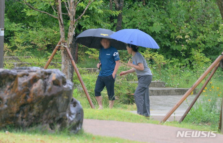 [전주=뉴시스] 김얼 기자 = 남부 지방에 장마가 시작된 가운데, 지난 주 금요일 오전까지 강수 예보가 없던 서울에 주말 사이 비가 내렸다. 다만 기상청은 이 비는 장맛비가 아니며, 중부 지방 장마는 빠르면 이달 말 시작될 것으로 봤다. 예기치 못한 비 소식으로 불볕더위는 한풀 꺾였지만, 낮 최고기온이 30도 안팎인 나날이 이어지며 후덥지근한 날씨는 계속될 전망이다. 사진은 선선한 여름 비가 내리는 지난 22일 전북 전주시 전주세병공원에서 시민들이 우산으로 비를 피하며 길을 지나는 모습. 2024.06.22. pmkeul@newsis.com