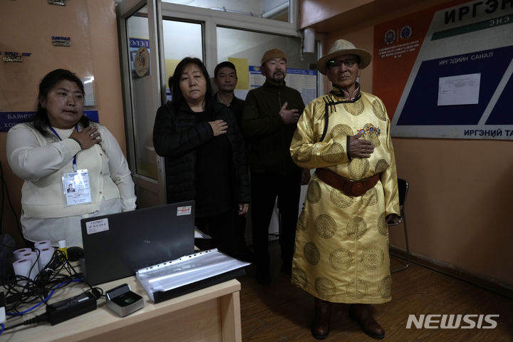 [울란바토르=AP/뉴시스] 28일(현지시각) 몽골 울란바토르의 한 투표소에서 투표소 직원과 유권자들이 투표에 앞서 국민의례를 하고 있다. 몽골 국민은 이날 126명의 국회의원을 선출하는 투표를 시작했다. 2024.06.28.