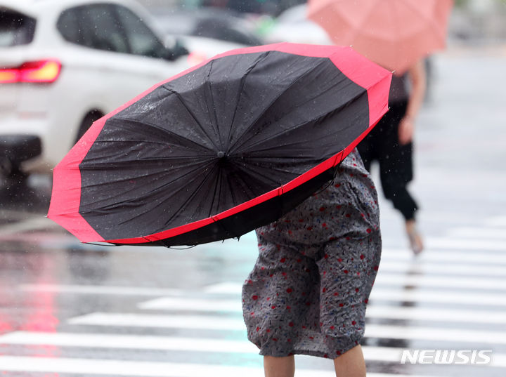 [서울=뉴시스] 김명년 기자 = 비가 내린 지난 20일 오후 서울 종로구 광화문 사거리에서 한 시민의 우산이 강풍에 뒤집히고 있다. 2024.07.20. kmn@newsis.com