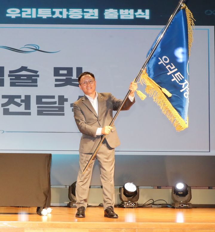 남기천 우리투자증권 대표가 1일 서울 여의도 TP타워 3층에서 열린 출범식에서 회사기를 흔들고 있다. (사진=우리투자증권 제공) photo@newsis.com *재판매 및 DB 금지