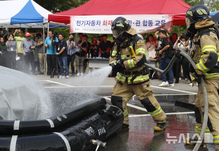 [인천=뉴시스] 김동영 기자 = 13일 오전 인천 연수구 송도2동 행정복지센터 옆 주차장에서 열린 ‘전기자동차 화재 대응 민·관 합동 교육’에서 소방대원들이 전기차 수조를 전개하고 있다. 이날 교육은 연수구청과 송도소방서 주최로 열렸으며, 지역 주민과 공무원 등 200여 명이 참여했다. 2024.08.13. dy0121@newsis.com 