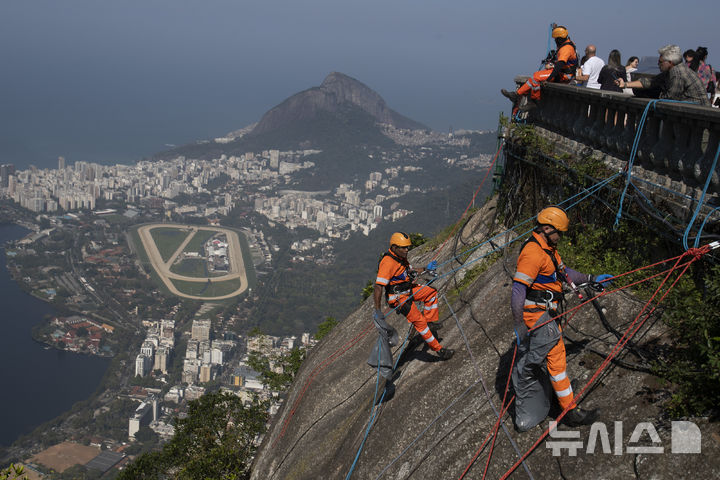 [리우데자네이루=AP/뉴시스]    Montanhistas escalam a montanha para limpar destroços deixados nas encostas da estátua de Jesus no Morro do Corcovado, no Rio de Janeiro, Brasil, no dia 22 (horário local). São escaladores certificados contratados para limpar as famosas montanhas da cidade, coletando não apenas lixo, mas também materiais inflamáveis ​​que representam risco de incêndio florestal. 2024.08.23.