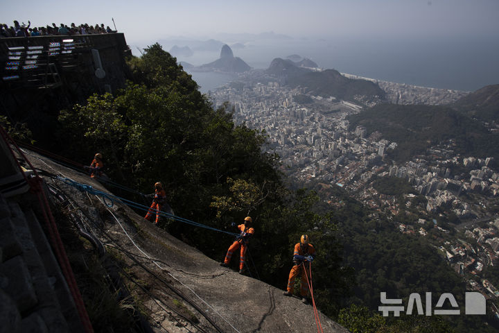 [리우데자네이루=AP/뉴시스]    Montanhistas escalam a montanha para limpar destroços deixados nas encostas da estátua de Jesus no Morro do Corcovado, no Rio de Janeiro, Brasil, no dia 22 (horário local). São escaladores certificados contratados para limpar as famosas montanhas da cidade, coletando não apenas lixo, mas também materiais inflamáveis ​​que representam risco de incêndio florestal. 2024.08.23.