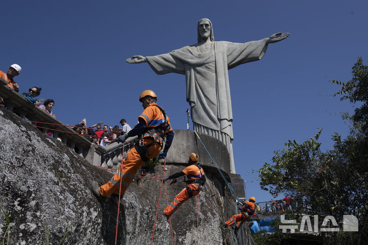 [리우데자네이루=AP/뉴시스]    Montanhistas escalam a montanha para limpar destroços deixados nas encostas da estátua de Jesus no Morro do Corcovado, no Rio de Janeiro, Brasil, no dia 22 (horário local). São escaladores certificados contratados para limpar as famosas montanhas da cidade, coletando não apenas lixo, mas também materiais inflamáveis ​​que representam risco de incêndio florestal. 2024.08.23.