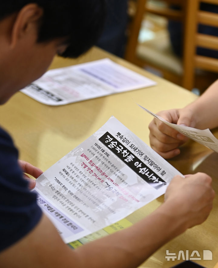 [광명=뉴시스] 김종택 기자 = 일본에 국권을 빼앗긴 경술국치일인 29일 경기도 광명시청 구내식당에서 직원들이 '흰 찬죽 나누기 행사'에 앞서 안내문을 살펴보고 있다.흰 찬죽 나누기 행사는 1910년 8월29일 일제에 의해 우리나라의 국권을 빼앗긴 후 선조들이 '국가적 치욕'을 잊지 않기 위해 흰 찬죽을 먹었던 전통에서 유래됐다. 2024.08.29. jtk@newsis.com