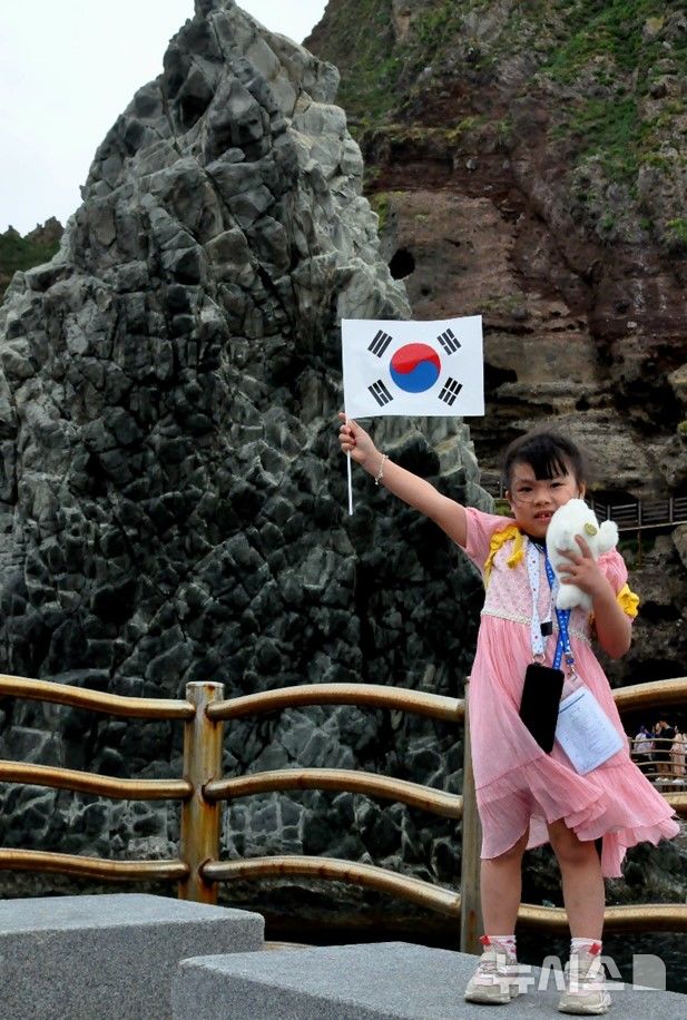 [서울=뉴시스] '2024 독도탐방' 참가자가 독도 입도 후 태극기를 흔드는 모습. 