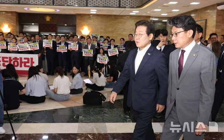 [서울=뉴시스] 고승민 기자 = 더불어민주당 이재명 대표 등 의원들이 19일 서울 여의도 국회에서 열린 제418회 국회(정기회) 제8차 본회의에 참석하고 있다.이들 뒤로 국민의힘 의원들이 입법 폭주 및 포퓰리즘 규탄 등의 피켓을 들고 구호를 외치고 있다. 2024.09.12. kkssmm99@newsis.com