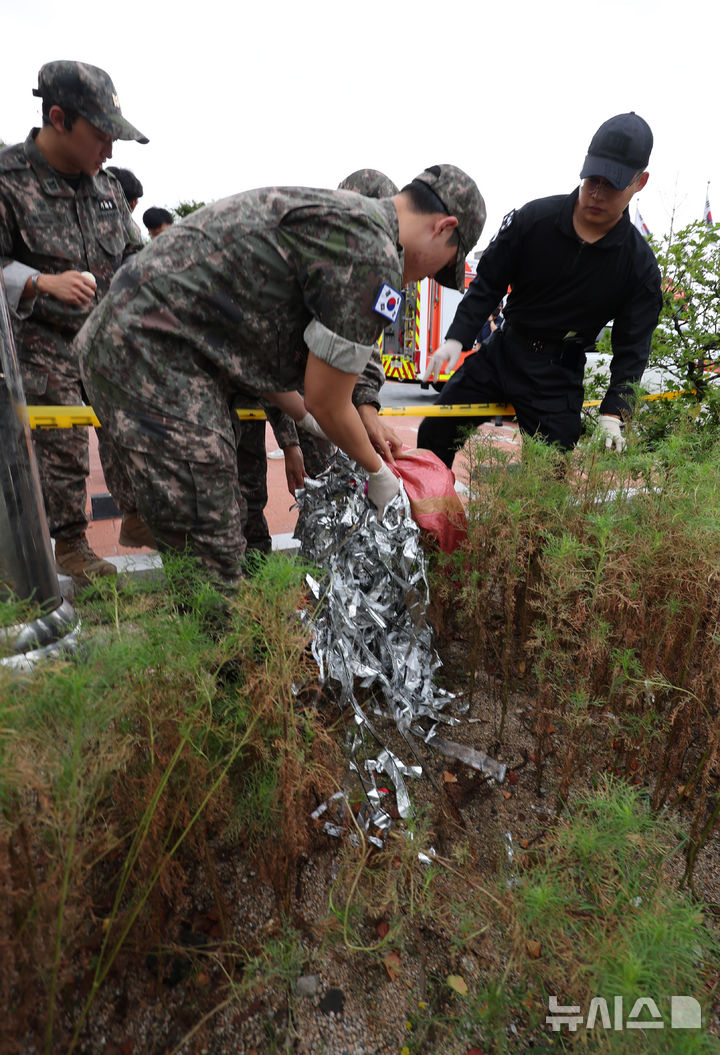 [서울=뉴시스] 김명원 기자 = 북한의 오물 풍선 도발이 지속되고 있는 가운데 20일 오전 서울 종로구 정부서울청사 야외주차장에 북한 오물풍선의 잔해가 떨어져 출동한 군부대가 수거를 하고 있다. 2024.09.20. kmx1105@newsis.com