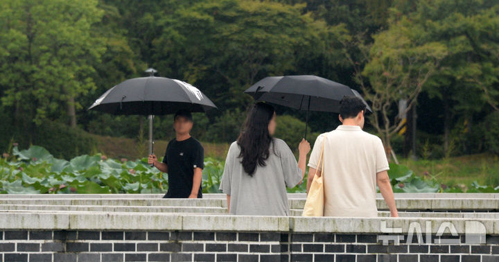 [전주=뉴시스] 김얼 기자 = 지난달 20일 전북 전주시 전주덕진공원을 찾은 시민들이 우산으로 비를 피하며 길을 지나고 있다. 2024.09.20. pmkeul@newsis.com