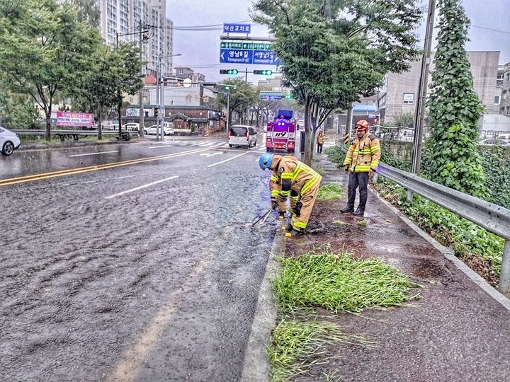 [울산=뉴시스] 구미현 기자 = 호우경보가 내려진 21일 울산 울주군 온산읍 덕산교차로에서 빗물 역류로 도로 맨홀 뚜껑이 열려 출동한 소방 대원이 안전 조치를 하고 있다. 2024.09.21. (울산소방본부 제공) photo@newsis.com *재판매 및 DB 금지