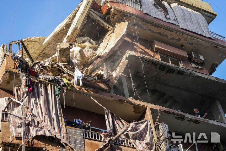 [베이루트=AP/뉴시스] 24일(현지시각) 레바논 베이루트 남부 외곽에서 주민들이 이스라엘의 공습으로 파괴된 건물 상황을 살피고 있다. 베냐민 네타냐후 이스라엘 총리는 이날 군 정보기지를 방문해 "우리의 전쟁 상대는 레바논 주민이 아닌 헤즈볼라"라며 헤즈볼라에 대한 공격을 이어갈 것임을 밝혔다. 2024.9.25.