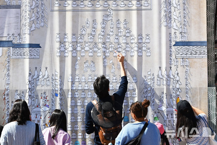 [수원=뉴시스] 김종택 기자 = 수원화성문화제가 열린 4일 경기도 수원시 팔달구 화성행궁 광장에서 '시민도화서 시즌2' 체험 행사에 참여한 시민들이 대형 화성행행도를 재연하는 벽화에 색칠하고 있다. 2024.10.04. jtk@newsis.com