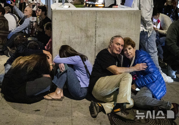 [ 텔아비브=신화/뉴시스] 10월 7일 가자전쟁 시작 1주년이 되는 날 이스라엘 중부 텔 아비브시에 대한 헤즈볼라의 공습으로 사이렌 경보에 따라 몸을 피하고 있는 시민들. 그러나 13일 공습에선 경보가 울리지 않아 수십명이 부상을 당했다. 2024.10.14. 