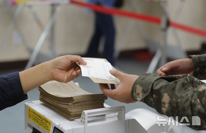  [인천=뉴시스] 김동영 기자 = 10·16 재보궐선거 사전투표 첫날인 11일 오전 인천 강화군 강화읍주민자치센터에 마련된 사전투표소에서 한 군인이 투표용지를 전달받고 있다. 2024.10.11. dy0121@newsis.com