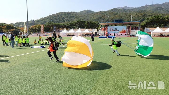 [과천=뉴시스] 체육대회에 참석한 어린이들이 가족들과 함께 '낙하산 달리기'를 하고 있다. (사진=과천시 제공). 2024.10.12. photo@newsis.com. *재판매 및 DB 금지 