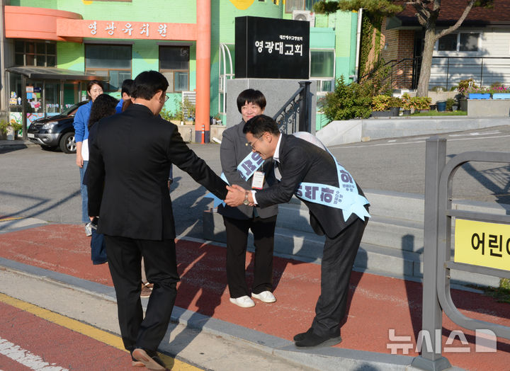 [영광=뉴시스] 이창우 기자=10·16 전남 영광군수 재선거 본투표를 사흘 앞둔 13일 오전 진보당 이석하 후보(오른쪽)가 영광대교회 앞에서 신도들에게 아침 인사를 하고 있다. 2024.10.13. lcw@newsis.com