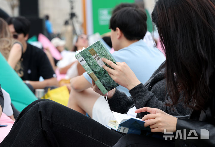 [서울=뉴시스] 김명원 기자 = 13일 서울 종로구 광화문 광장 서울 야외도서관 책마당에서 한강 작가의 노벨문학상 수상을 축하하기 위한 마련된 특별 전시에서 시민들이 한강 작가의 책을 읽고 있다. 이번 특별전은 ‘책읽는 서울광장’과 ‘광화문 책마당’, ‘책읽는 맑은냇가’ 등 3곳에서 진행된다. ‘채식주의자’ ‘소년이 온다’ ‘검은 사슴’ ‘바람이 분다, 가라’ 등 도서 10종, 총 216권이 한국어를 비롯해 영어, 일본어, 중국어, 아랍어, 그리스어 등 20개 언어로 된 번역본을 함께 전시한다. 한강은 지난 2016년 한국인 최초로 세계 3대 문학상인 '부커상'을 받았고, 지난해에는 프랑스 4대 문학상인 '메디치상'을 수상했다. 2024.10.13. kmx1105@newsis.com