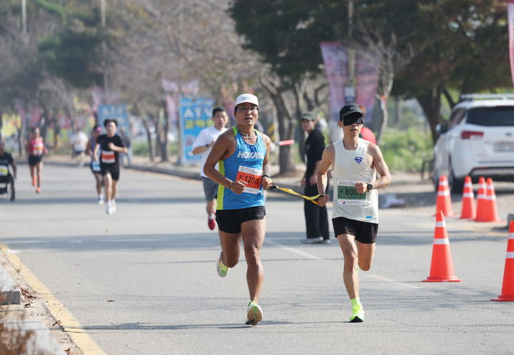 [태안=뉴시스] 지난 12일 충남 태안 안면읍 꽃지해수욕장 일원에서 열린 '제5회 문화체육관광부장관배 충남 태안 전국어울림마라톤대회'에 참가한 장애인비·장애인 선수가 끈으로 서로의 팔을 묶은채 함께 달리고 있다. (사진=태안군 제공) 2024.10.14. *재판매 및 DB 금지