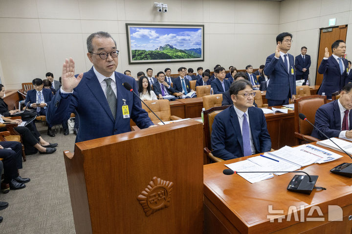 [서울=뉴시스] 국회사진기자단 = 정인섭 한화오션 거제사업장 사장이 15일 오후 서울 여의도 국회에서 열린 환경노동위원회의 경제사회노동위원회, 중앙노동위원회, 최저임금위원회 등에 대한 국정감사에서 선서하고 있다. 정 사장 뒤로 뉴진스 멤버 하니 팜이 참고인 자격으로 앉아 있다. 2024.10.15. photo@newsis.com