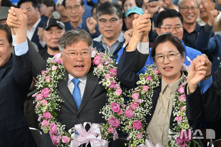 [영광=뉴시스] 이영주 기자 = 더불어민주당 장세일 영광군수 당선인이 10·16 재·보궐선거가 치러진 16일 오후 전남 영광군 선거사무실에서 아내 정수미씨와 함께 만세를 부르고 있다. 2024.10.16. leeyj2578@newsis.com