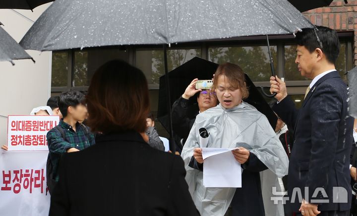 [청주=뉴시스] 서주영 기자 = 김영호 국회 교육위원회 위원장이 18일 충북대학교 의과대학 앞에서 발언하는 전국의대학부모연합 관계자에게 우산을 씌워주고 있다. 2024.10.18. juyeong@newsis.com